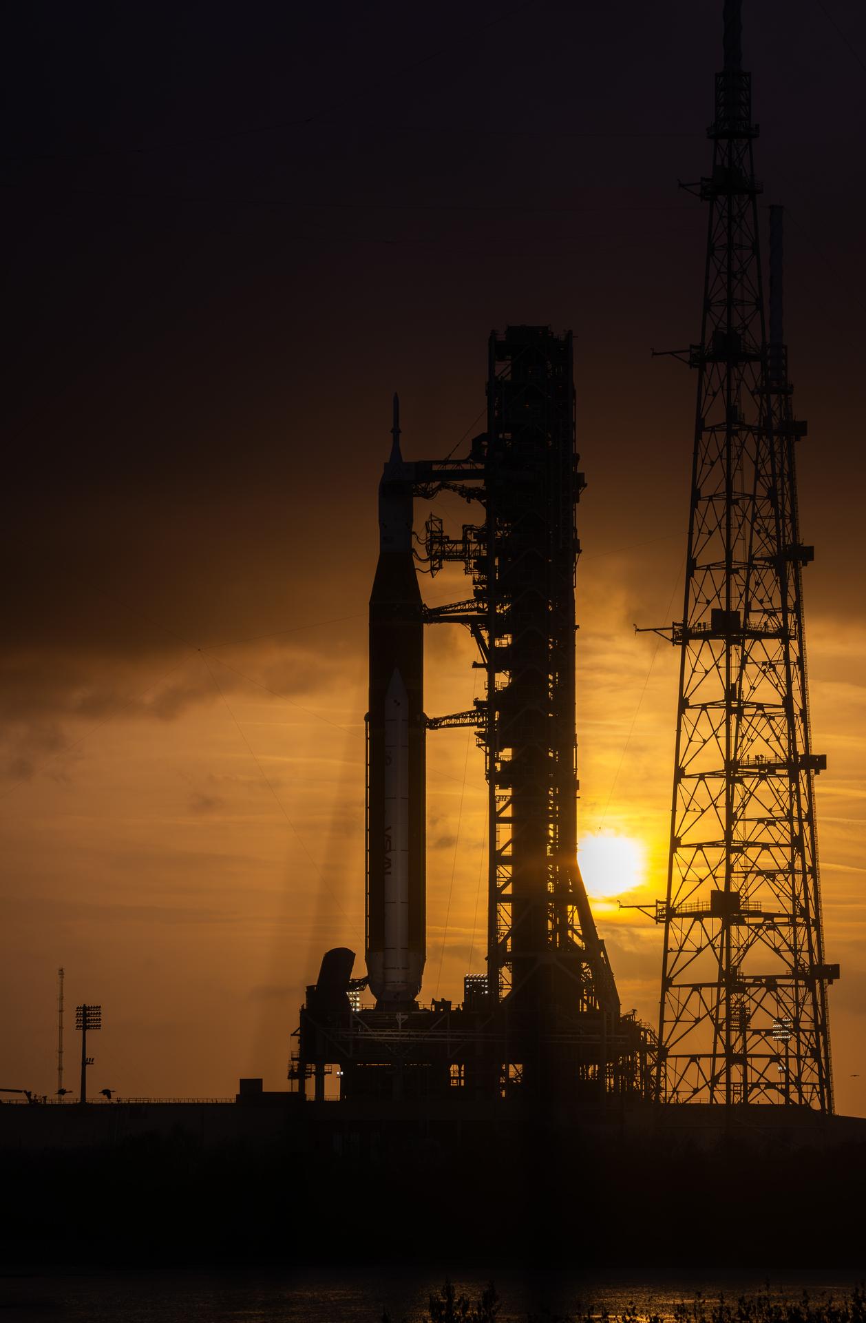 This image shows a sunset of NASA’s SLS (Space Launch System) and Orion spacecraft at NASA’s Kennedy Space Center. NASA's massive Crawler-Transporter, upgraded for the Artemis program, carried the powerful SLS rocket and Orion spacecraft on the Mobile Launcher from the Vehicle Assembly Building to Launch Pad 39B at Kennedy Space Center in preparation for the Artemis II mission.